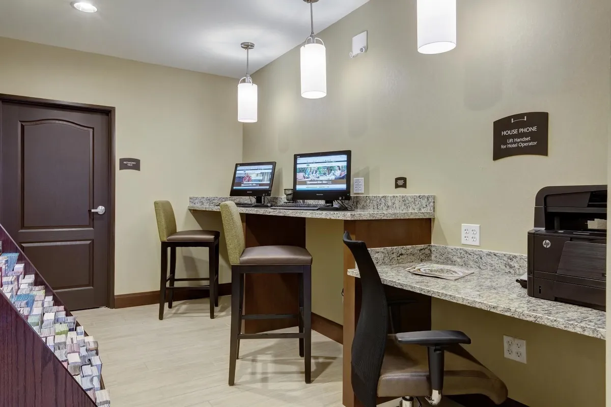 A well-equipped work zone with computers, a granite countertop, bar stools, and practical amenities like a printer and house phone. The space is designed for productivity, whether for business or personal needs.