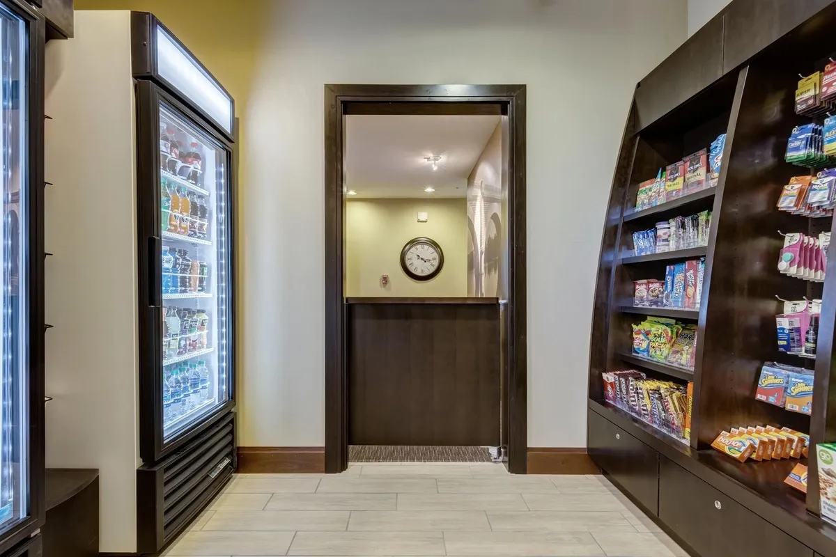 A convenient snack area with a refrigerated beverage display, snack shelves, and a clock, inviting guests to grab a quick refreshment or enjoy a casual break between activities.