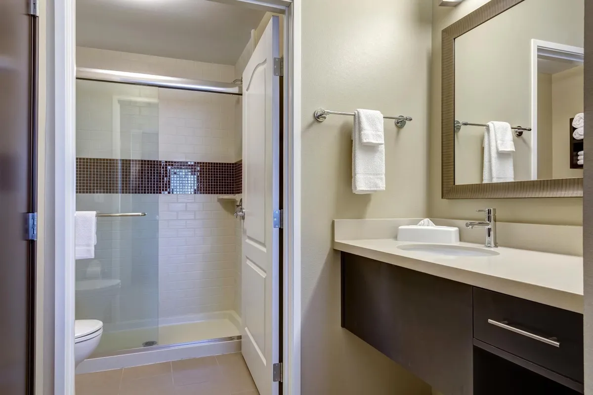 A modern bathroom with a sleek shower area, wide vanity, and large mirror. The space is stocked with fresh towels and toiletries, offering a refreshing and inviting environment for daily routines.
